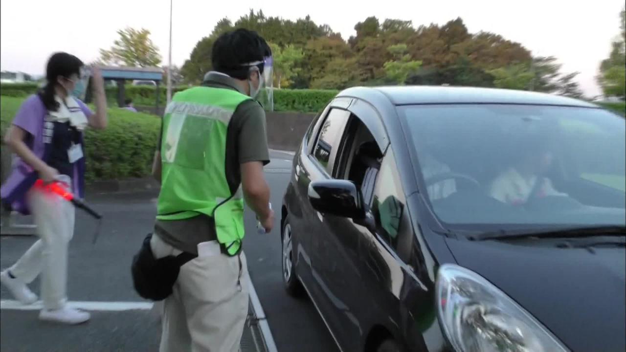 画像: 駐車場の入口で入場者の検温をする係員