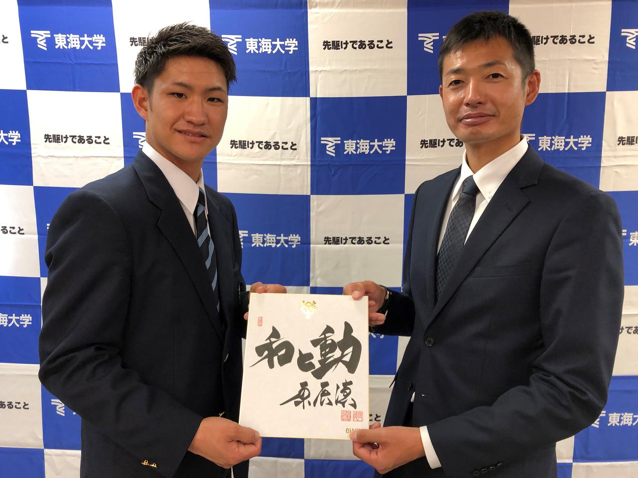 画像: 巨人の原辰徳監督からの色紙を手に、青木高広スカウト(右)と記念写真に納まる東海大海洋学部4年の加藤廉。